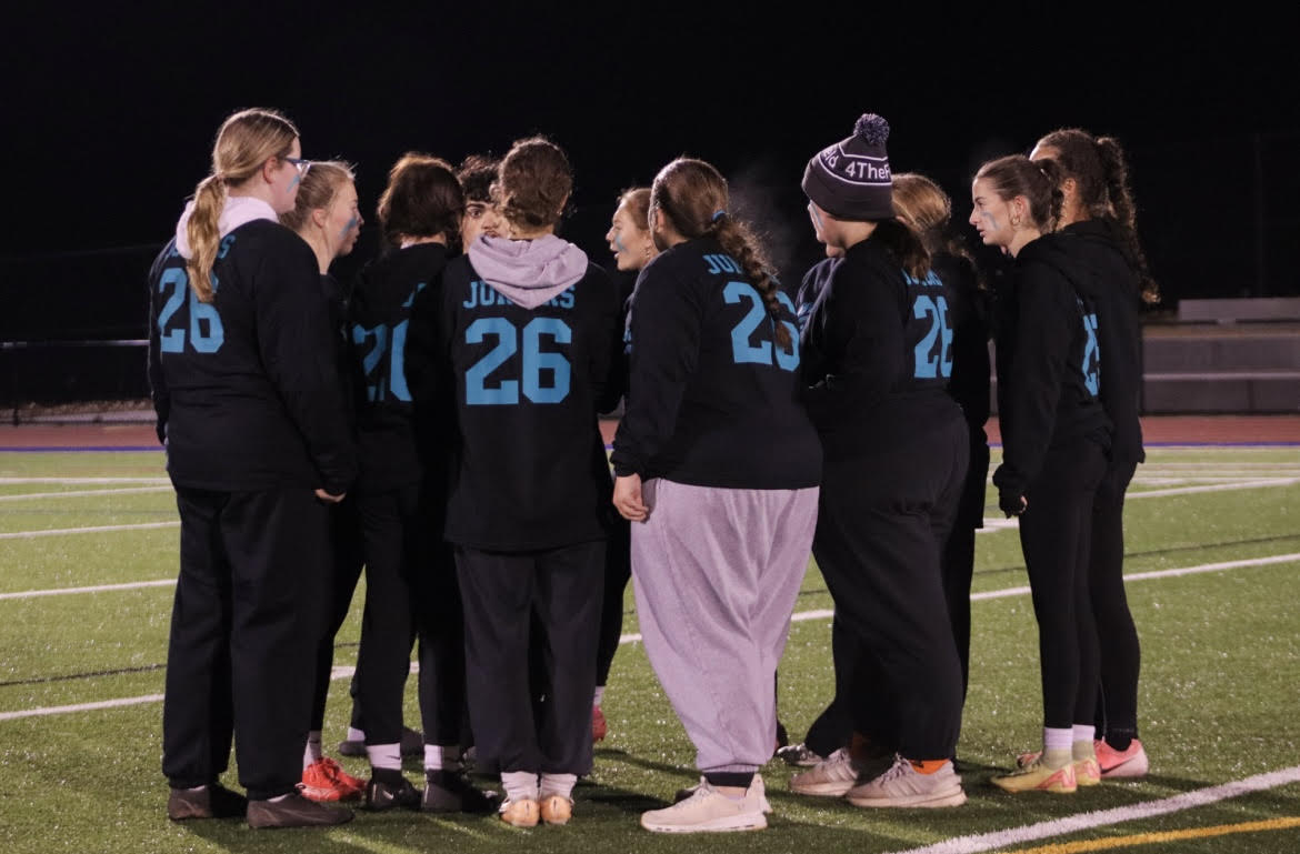 Juniors, Jordyn Manning, Madyson Manning, Sam Stewart, Gemma Conca, Clair Somers, Emma Nichalson, and Kelsey Turner, huddle together as they plan their play for a game against the Seniors.