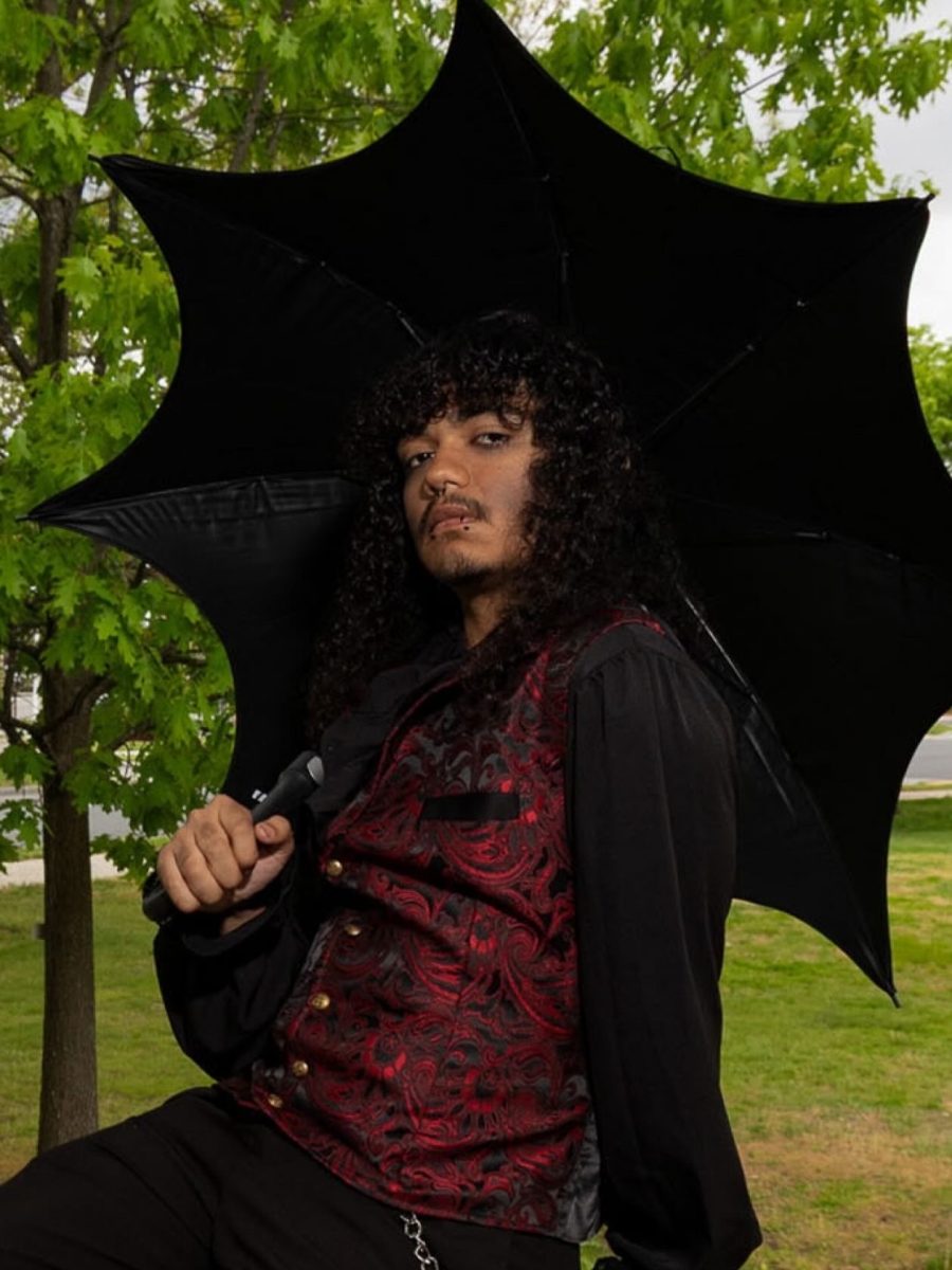 Josh Hernandez sitting under his gothic umbrella, posing as a vampire.
